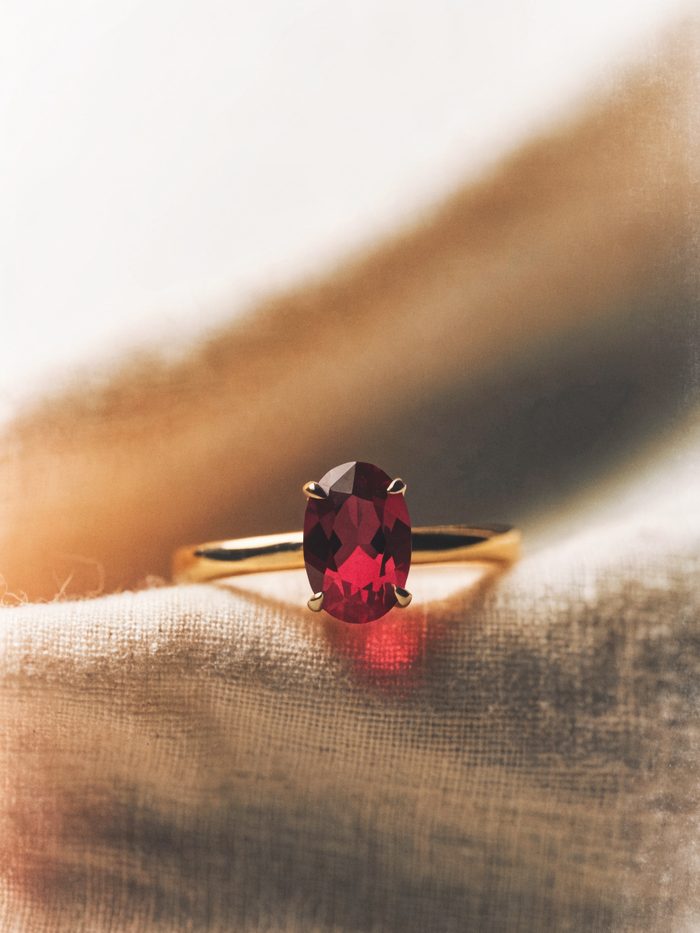 An oval-cut red ruby ring in yellow gold on linen