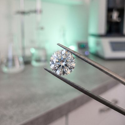 A lab-grown brilliant diamond held in tweezers in a laboratory